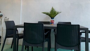 Zona pranzo con tavolo e sedie, una pianta in vaso e decorazioni a tema pesce sulle pareti.