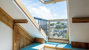 A wooden staircase with a glass window leading to a balcony overlooking a residential area.