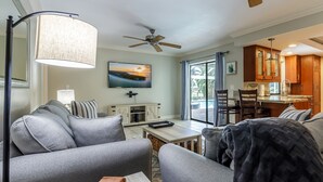 Ein modernes Wohnzimmer mit grauen Sofas, einem Couchtisch und einem Deckenventilator.
