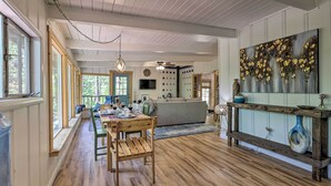 Un vaste salon doté d’un plancher en bois, un coin repas avec une table et des chaises, un canapé et un grand tableau abstrait accroché au mur.