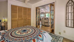 Une chambre à coucher avec un grand lit, une armoire en bois et une vue sur une autre pièce grâce à une porte ouverte.