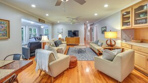 A spacious living room with a wooden floor, a ceiling fan, a TV, and a dining area with a table and chairs. - Spacious Lake Hartwell Home w/ Private Boat Dock! (Anderson)