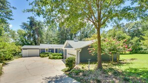 A two-story house with a garage, surrounded by a well-maintained garden and trees. - Spacious Lake Hartwell Home w/ Private Boat Dock! (Anderson)