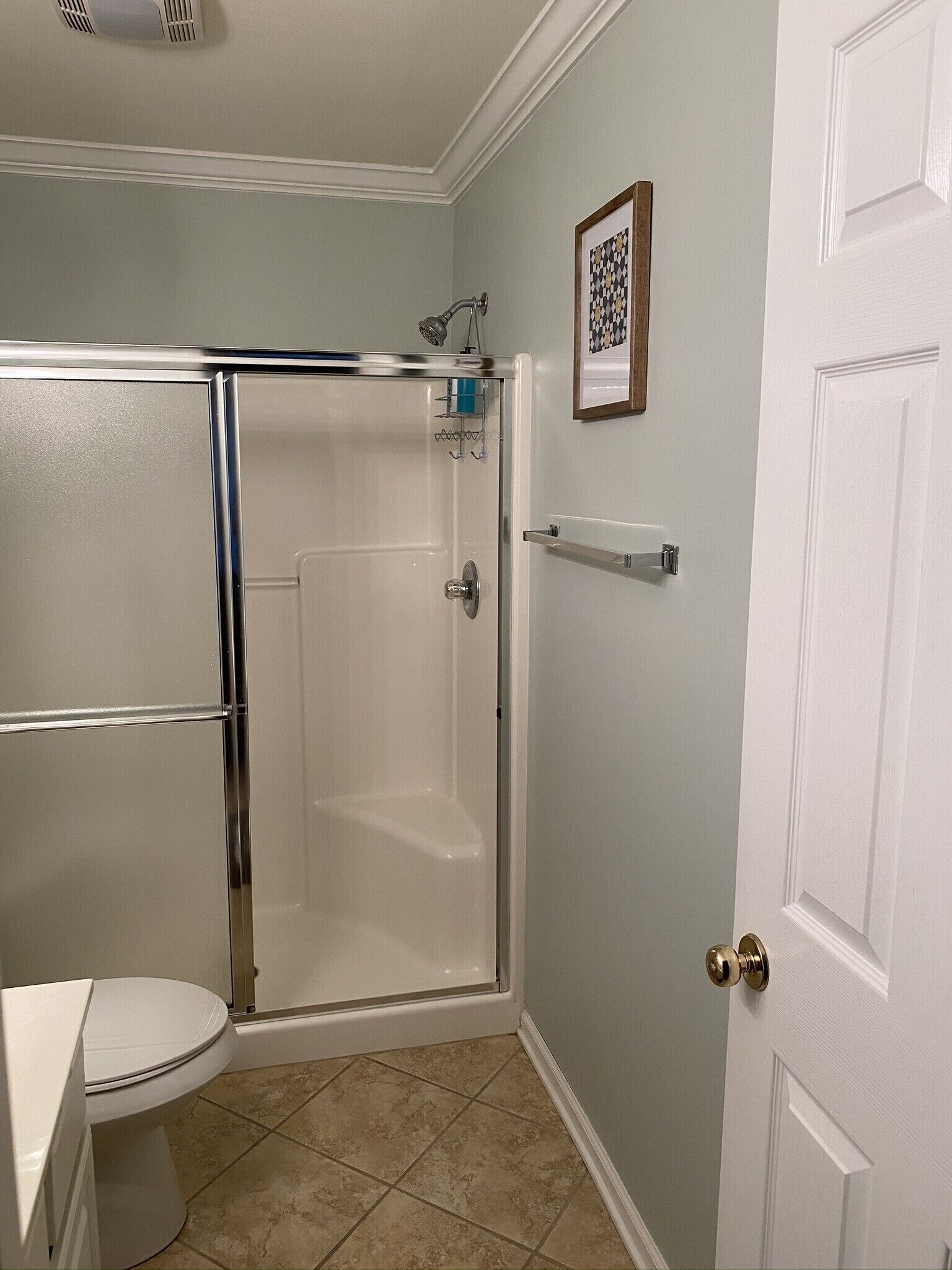 Une salle de bain avec une douche à parois de verre, des toilettes et une porte dotée d’une poignée.