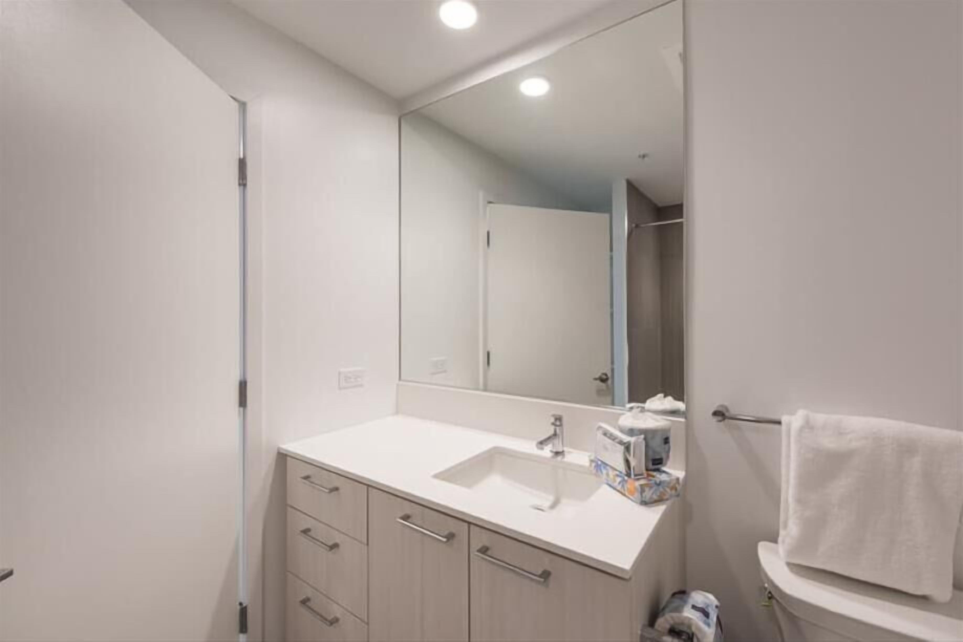 Une salle de bain moderne avec un lavabo blanc, un miroir et un porte-serviettes.