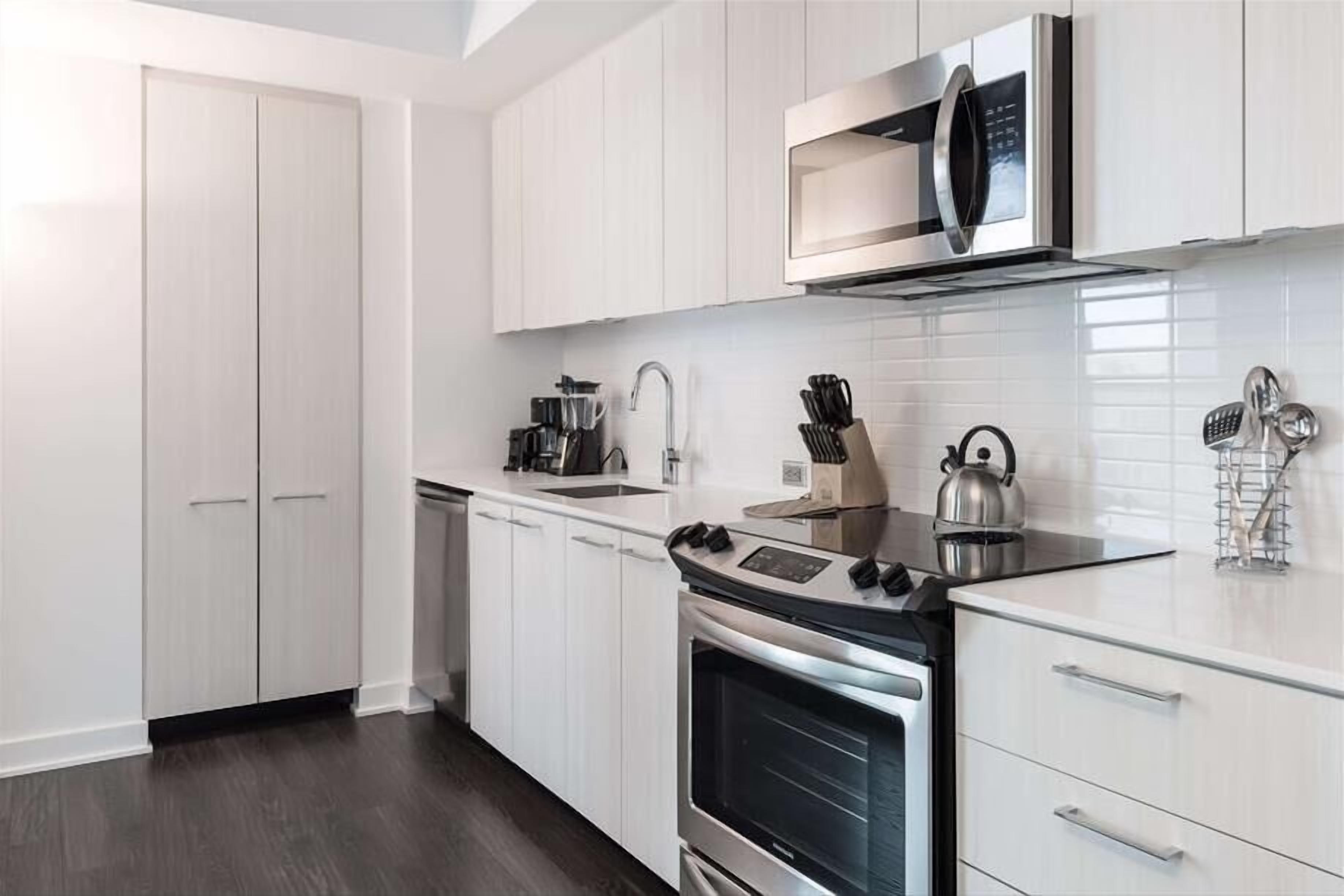 Una cocina moderna con armarios blancos, electrodomésticos de acero inoxidable y encimera negra.