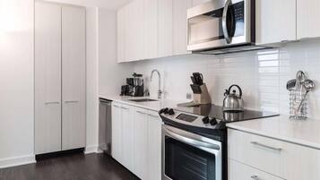 Una cocina moderna con armarios blancos, electrodomésticos de acero inoxidable y encimera negra.