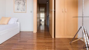 A modern room with a wooden floor, a white sofa, a lamp, and a door leading to another room. - Chueca Apartments I - Duplex in the Center of Madrid (Madrid)