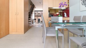A modern kitchen with a glass dining table, white chairs, and purple orchids. - Chueca Apartments I - Duplex in the Center of Madrid (Madrid)