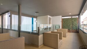 A modern interior with wicker furniture, a glass railing, and a view of the city. - Chueca Apartments I - Duplex in the Center of Madrid (Madrid)