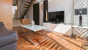 Un salon moderne avec un escalier, un téléviseur à écran plat et une lampe décorative.