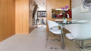 Une cuisine moderne avec des meubles en bois, une table à manger en verre et des chaises blanches.