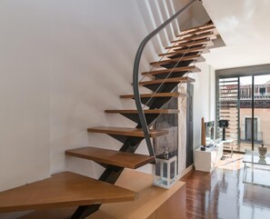 A modern staircase with wooden steps and metal railings, leading to a glass door.