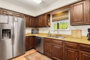 A kitchen with wooden cabinets, stainless steel appliances, a window with a view, and a kitchen island.