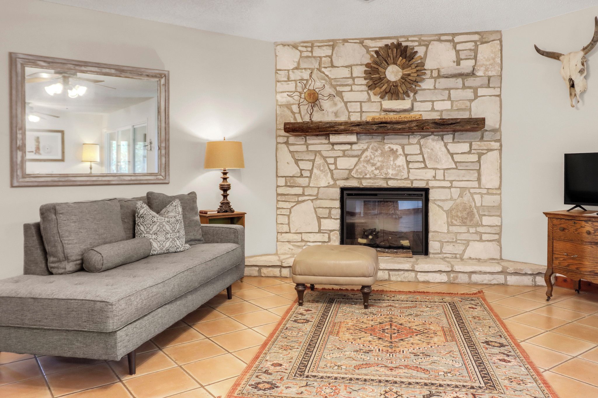 A living room with a stone fireplace, a sofa, a rug, and a television.
