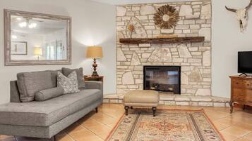 A living room with a stone fireplace, a sofa, a rug, and a television.