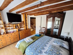 A bedroom with a bed, wooden dresser, television, and a mirror.