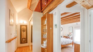 Un couloir doté d’un plancher en bois, d’une plante en pot et d’un meuble en bois muni d’étagères.