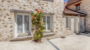Un bâtiment en pierre doté de deux fenêtres, l’une ornée d’une grille décorative et l’autre d’un petit balcon.