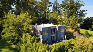 A modern two-story house surrounded by dense trees.