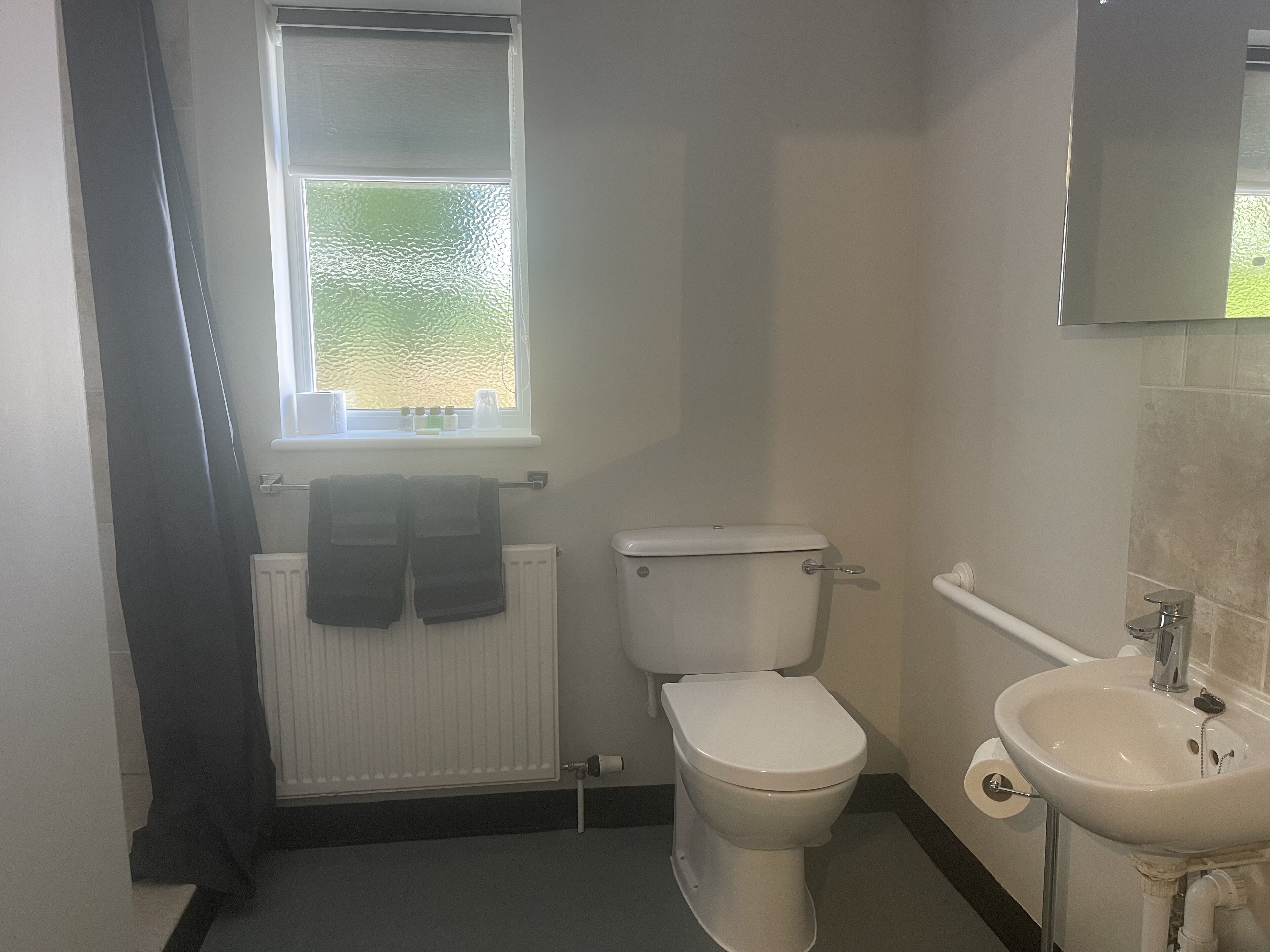 Et lille, enkelt badeværelse med toilet, vask og et vindue.