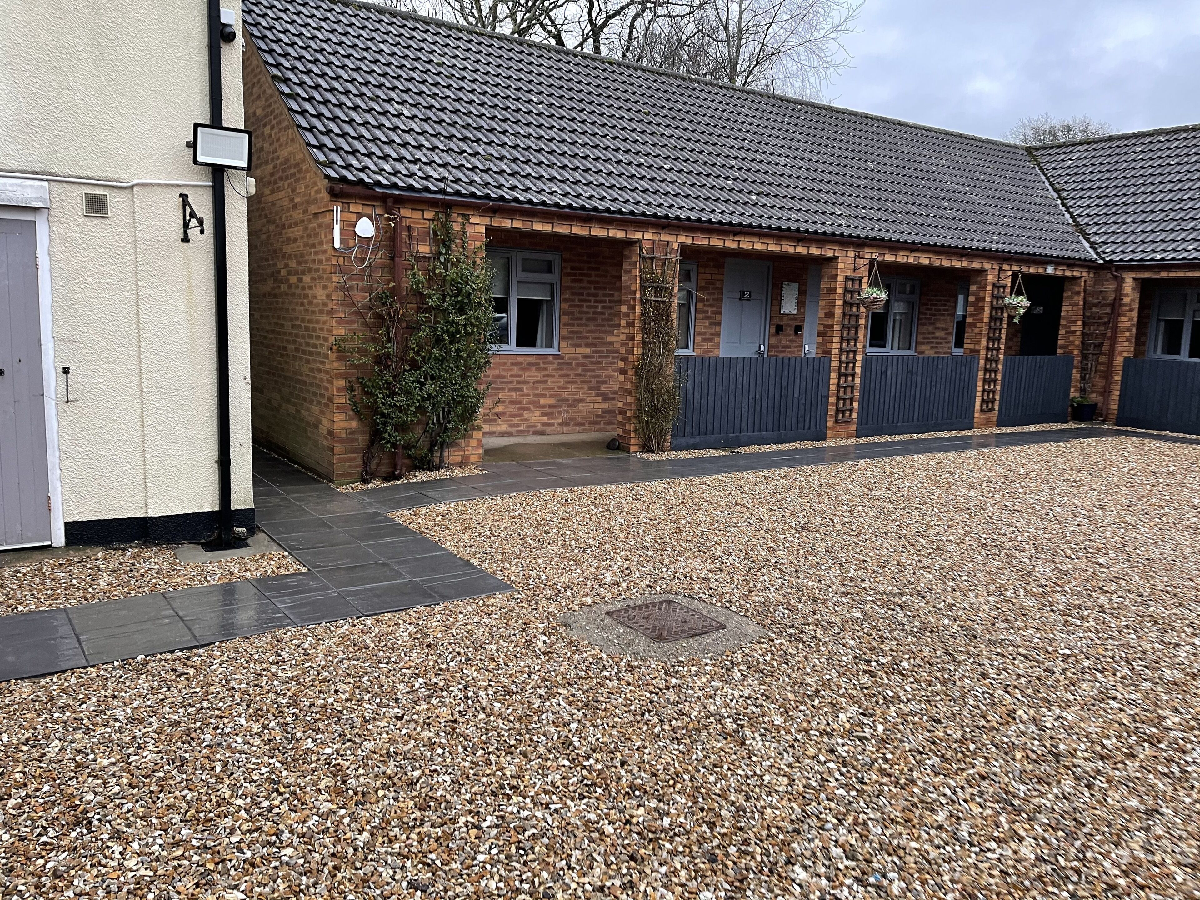 A building with a tiled roof, brick walls, and a gravel driveway.