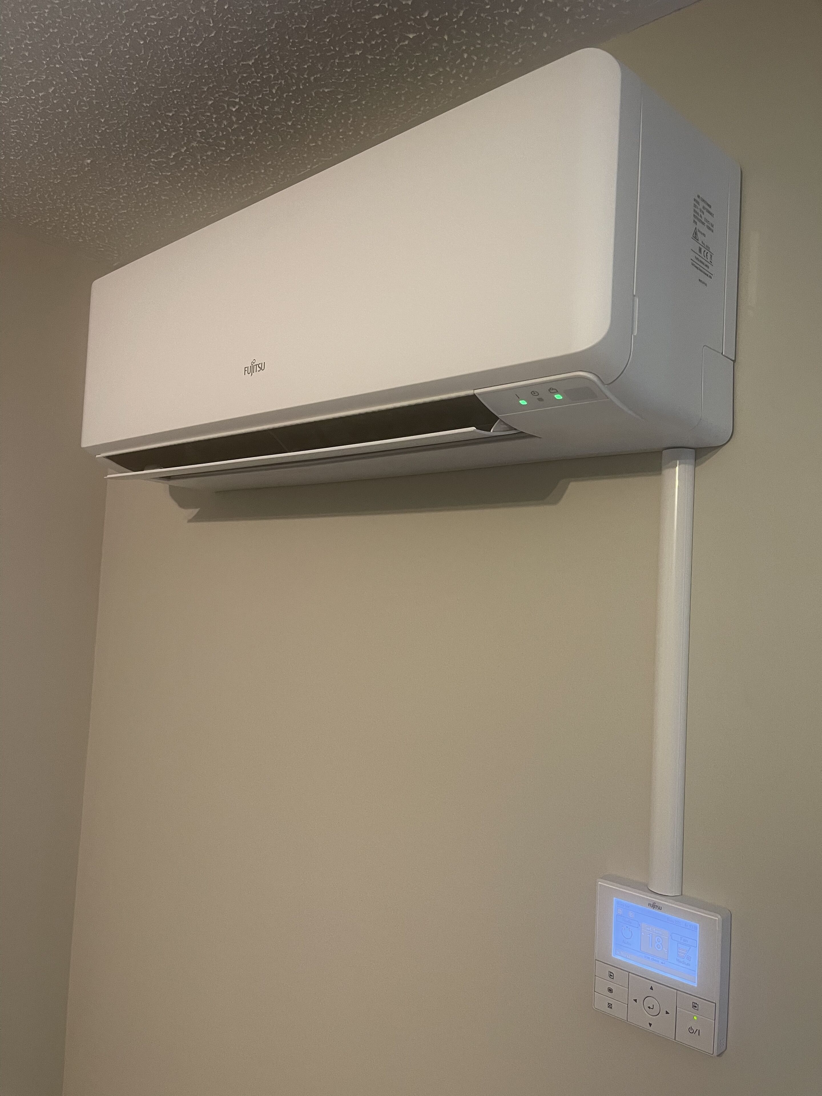 En vægmonteret aircondition med kontrolpanel nedenunder.