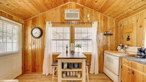 A wooden cabin interior with a kitchen, dining area, and a clock on the wall. - Couples Cabin w/ Luxury Deck, 1 Mi to Canyon Lake! (Canyon Lake)
