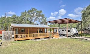 Una cabaña de madera con un porche y un área techada, junto a una caravana Jayco.