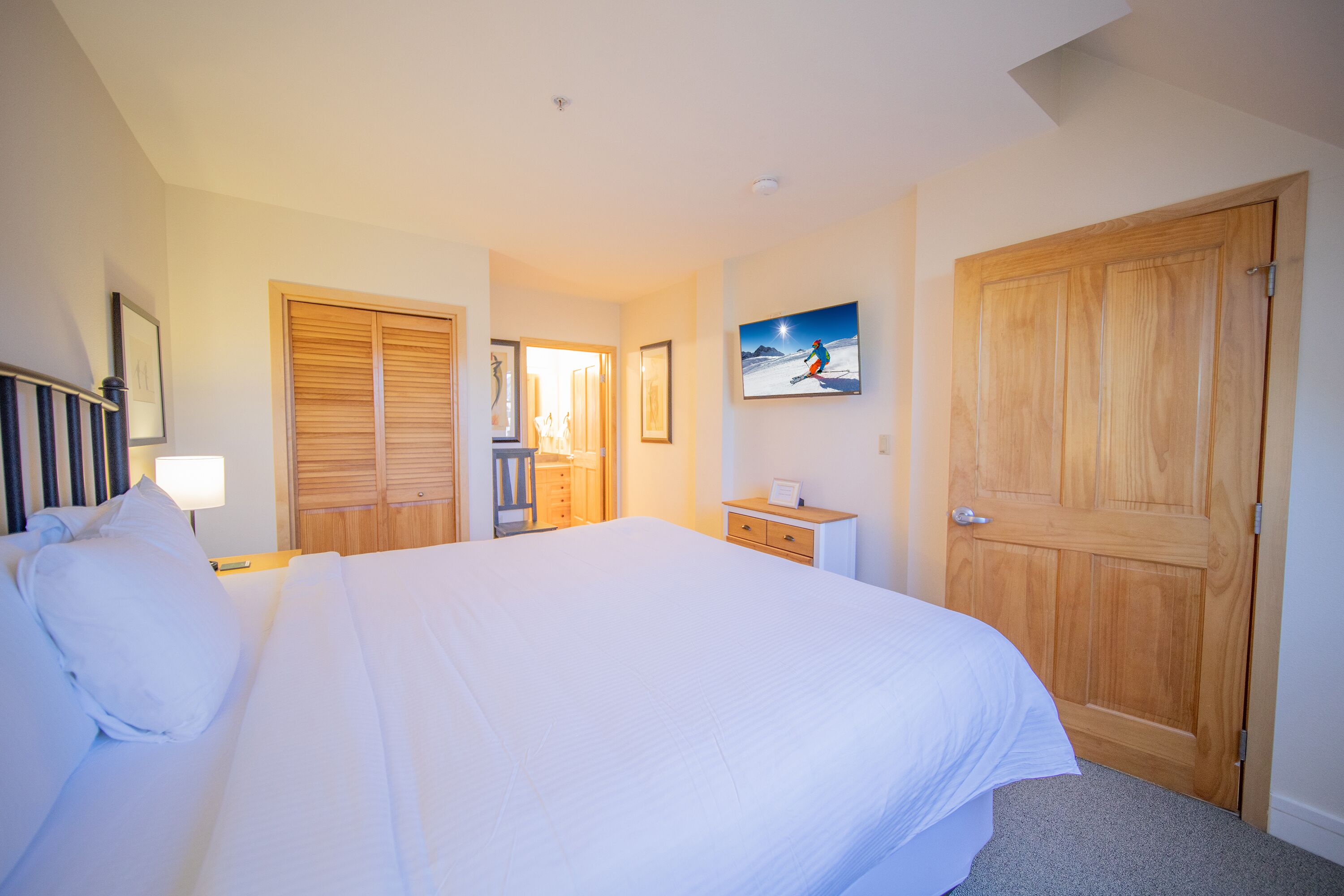 Une chambre d’hôtel avec un grand lit, une armoire en bois, une table de chevet et un tableau au mur.