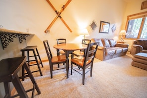 A cozy living room with a wooden dining table, chairs, a sofa, and a window with natural light. - Arapahoe Lodge 8105 (Keystone)