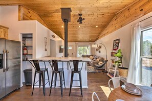 Enjoy meals in the spacious kitchen and dining area, featuring a central island with bar stools, oven, and wooden table.