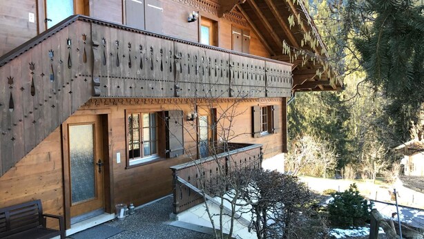 A wooden building with a balcony, a staircase, and a small garden area with snow. - Halten (Hofmann) by Interhome (Zweisimmen)