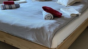 A wooden-paneled room with a bed, pillows, a rolled towel, and a towel on the bed. - Halten (Hofmann) by Interhome (Zweisimmen)