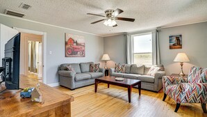 A living room with a grey sofa, a patterned armchair, a wooden coffee table, and a ceiling fan. - Decatur Farmhouse Getaway w/ Deck & Backyard (Decatur)