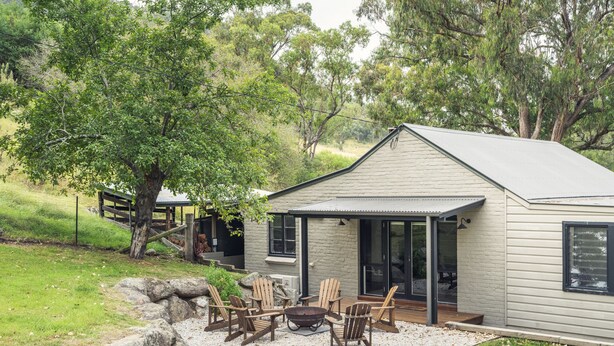 A small, single-story house with a covered patio area, outdoor seating, and a fire pit. - The River Cottage - Idyllic river side cottage (Joadja)