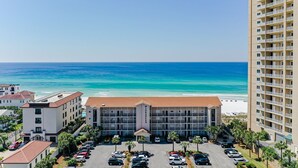 A hotel with a central building, parking lot, and ocean view. - Beautiful 4th FL Condo, Gulf Front, Seasonal Beach Service (Miramar Beach)
