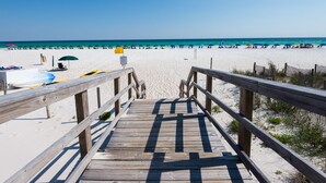 A wooden boardwalk leading to a beach with umbrellas and beach chairs. - Beautiful 4th FL Condo, Gulf Front, Seasonal Beach Service (Miramar Beach)