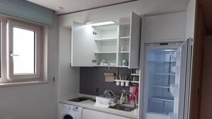 A compact kitchen with a built-in washing machine, a sink, and a refrigerator. - Sunrise Hotel Junior Suite room11F  (Sokcho-si)