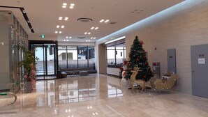 A spacious lobby with a Christmas tree, seating area, and a glass entrance. - Sunrise Hotel Junior Suite room11F  (Sokcho-si)