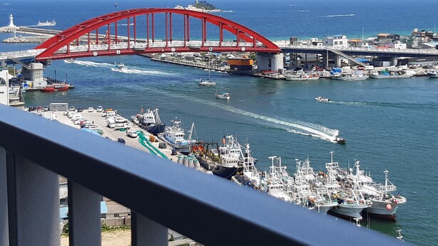 A coastal view with a prominent red bridge, boats, and a marina. - Sunrise Hotel Junior Suite room11F  (Sokcho-si)