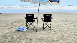 Twee strandstoelen met de aanduiding 'Pax bleu' op een zandstrand, met een grote strandparasol.
