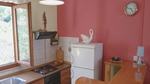 A compact kitchen with wooden cabinets, a white refrigerator, a stove, and a sink. - Apartment Kata - Two-Bedroom Apartment with Balcony and Garden View (Lumbarda)