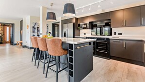 A modern kitchen with a central island, bar stools, and pendant lighting. - Large 6 bedroom luxury holiday home in the Cotswolds with a hot tub - Folly View (Faringdon)