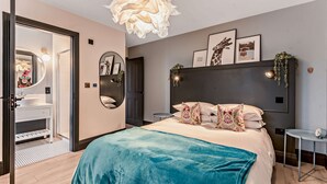 A modern bedroom with a large bed, a vanity with a mirror, and a unique ceiling light fixture. - Large 6 bedroom luxury holiday home in the Cotswolds with a hot tub - Folly View (Faringdon)