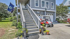 Ein zweistöckiges Haus mit Garage, einer Treppe zum Obergeschoss und einem roten Golfwagen auf der Auffahrt.