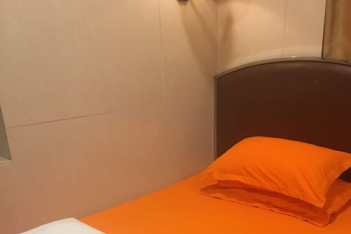 Un lit simple avec un matelas orange et un oreiller blanc.
