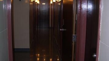 A hotel hallway with a polished floor, a clock on the wall, and doors leading to rooms.