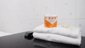Un bagno con un asciugamano e una bottiglia di sapone per le mani su una superficie nera.
