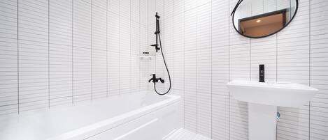 A modern bathroom with a white bathtub, a sink, and a mirror.